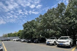 Een parkeerplaats met meerdere auto's onder bomen.