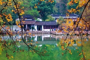 A traditional building with a reflection in the water, surrounded by trees. - Greentree Inn Jiangsu Suzhou International Film City South Jinshan Road Express Hotel (Suzhou)