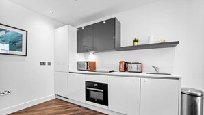 Eine moderne Küche mit weißen Schränken, einem eingebauten Backofen, einer Mikrowelle und einem Toaster.