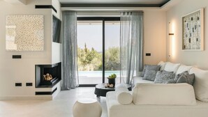Ein modernes Wohnzimmer mit einem weißen Sofa, einem Kamin und Blick auf einen Pool.
