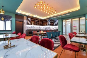 A restaurant with marble tables, red chairs, and a modern chandelier. - Jupian Movie Hotel (Pingyang Aojiang Xinhenan Road) (Pingyang)