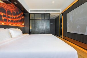 Una habitación de hotel con una cama grande, una pantalla montada en la pared y un mural con temática de teatro.