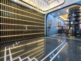 A modern lobby with a reflective floor, a vertical light panel, and a curved shelving unit with various items.