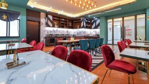 A modern restaurant with marble tables, red velvet chairs, and a geometric patterned wall. - Jupian Movie Hotel (Pingyang Aojiang Xinhenan Road) (Pingyang)