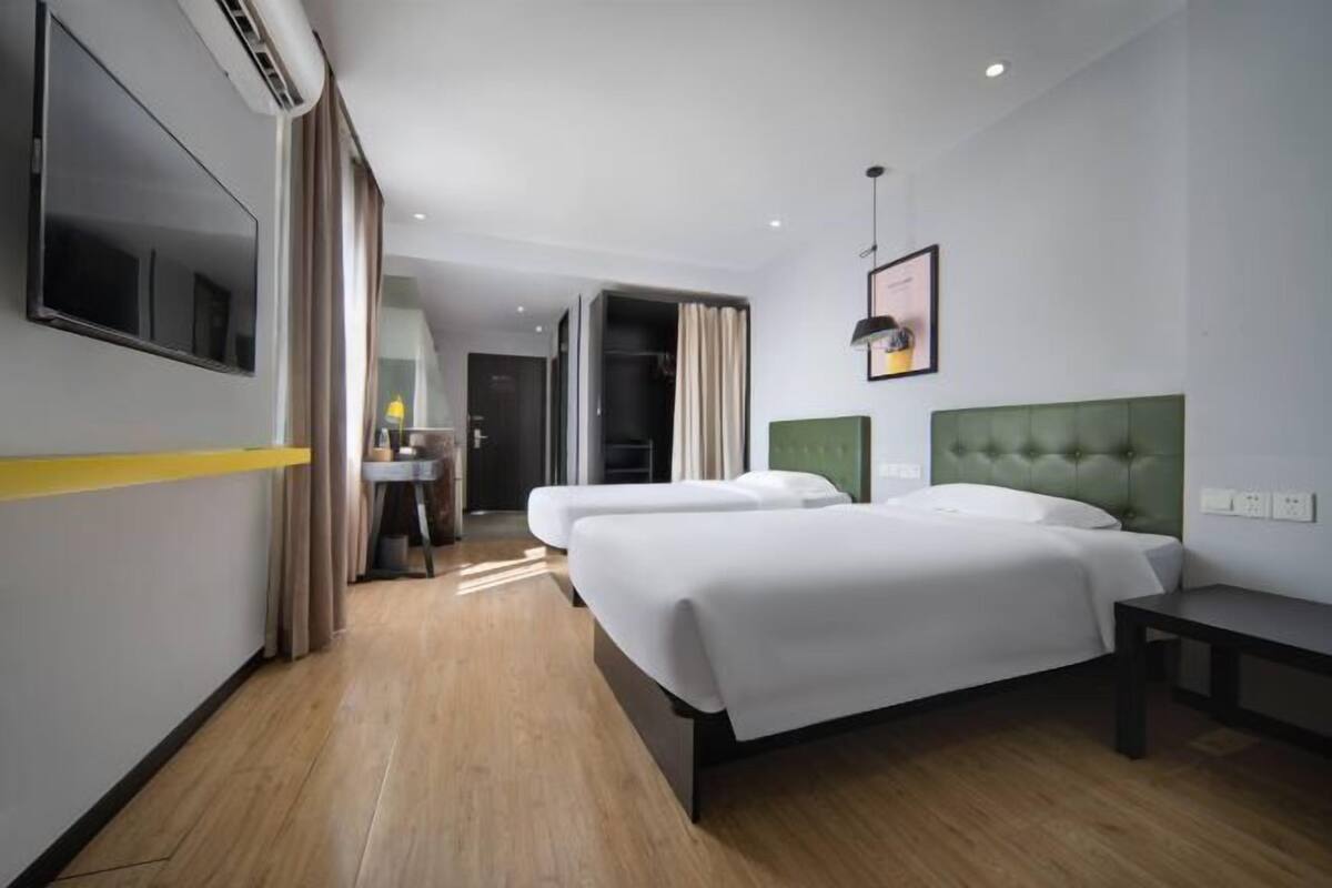Une chambre d’hôtel avec deux lits, un bureau et une télévision.