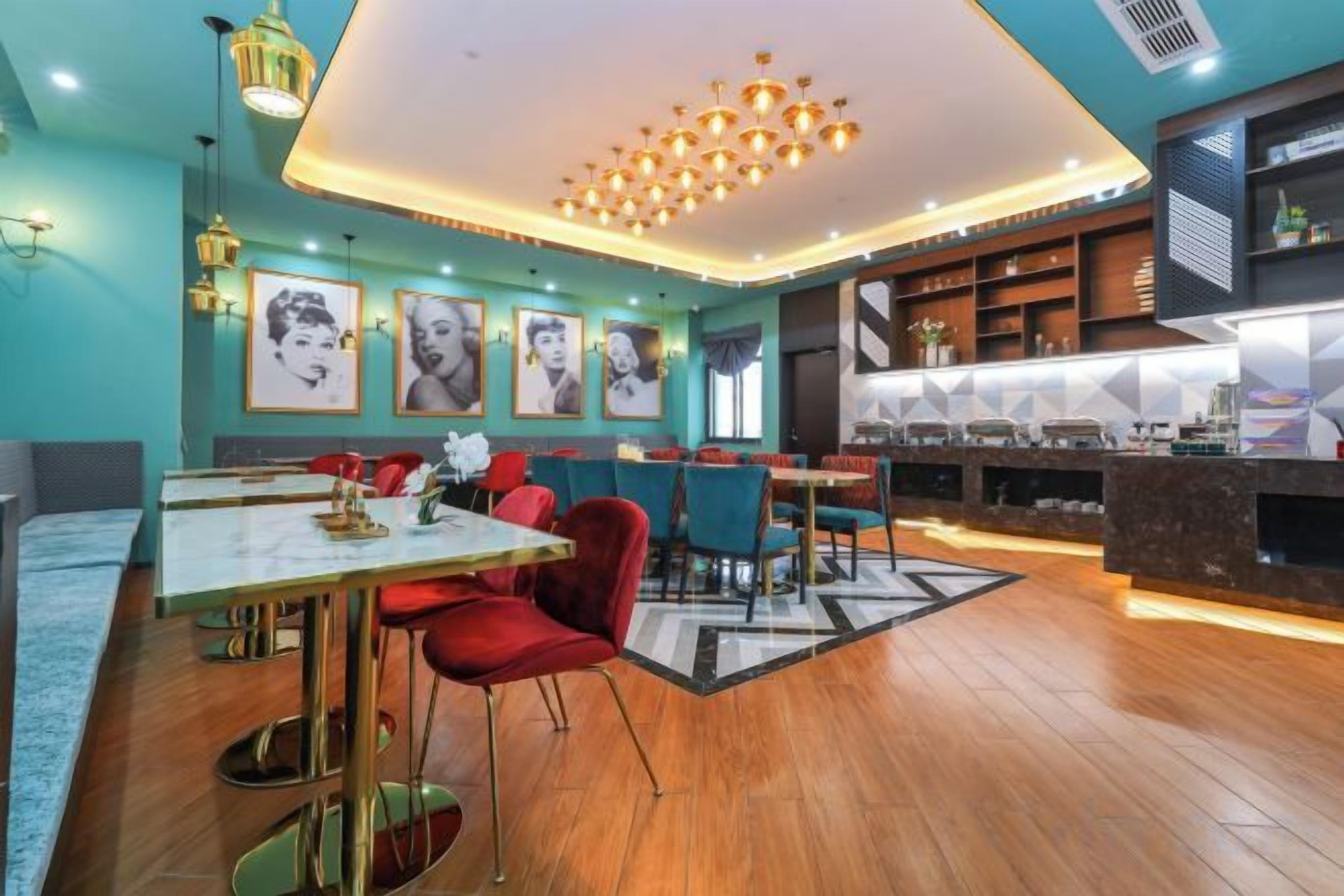 A modern restaurant with a bar area, wooden flooring, and a central chandelier.
