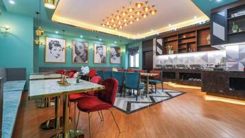 A modern restaurant with a bar area, wooden flooring, and a central chandelier.