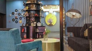 A modern interior with a central decorative column, a round table with a vase, and a seating area with a blue chair. - Jupian Movie Hotel (Pingyang Aojiang Xinhenan Road) (Pingyang)