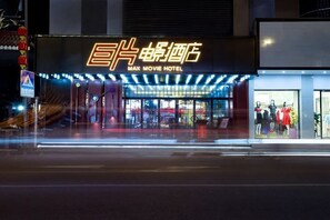 A building with a neon sign reading "MAX MOVIE HOTEL" and a storefront with mannequins displaying clothing. - Jupian Movie Hotel (Pingyang Aojiang Xinhenan Road) (Pingyang)