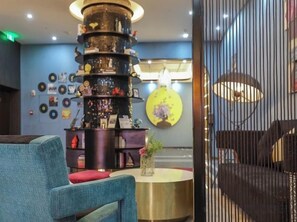 A bar area with a central column, a round table with a vase, and a blue chair. - Jupian Movie Hotel (Pingyang Aojiang Xinhenan Road) (Pingyang)