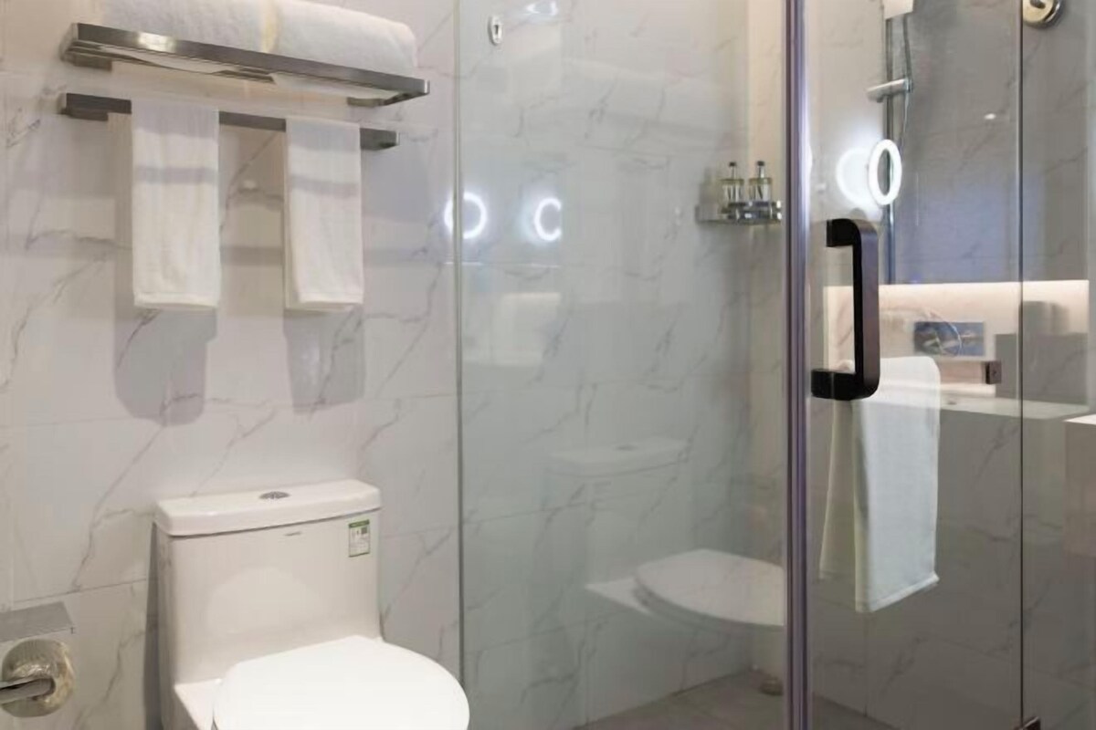 A modern bathroom with a glass shower enclosure, a toilet, and a towel rack.