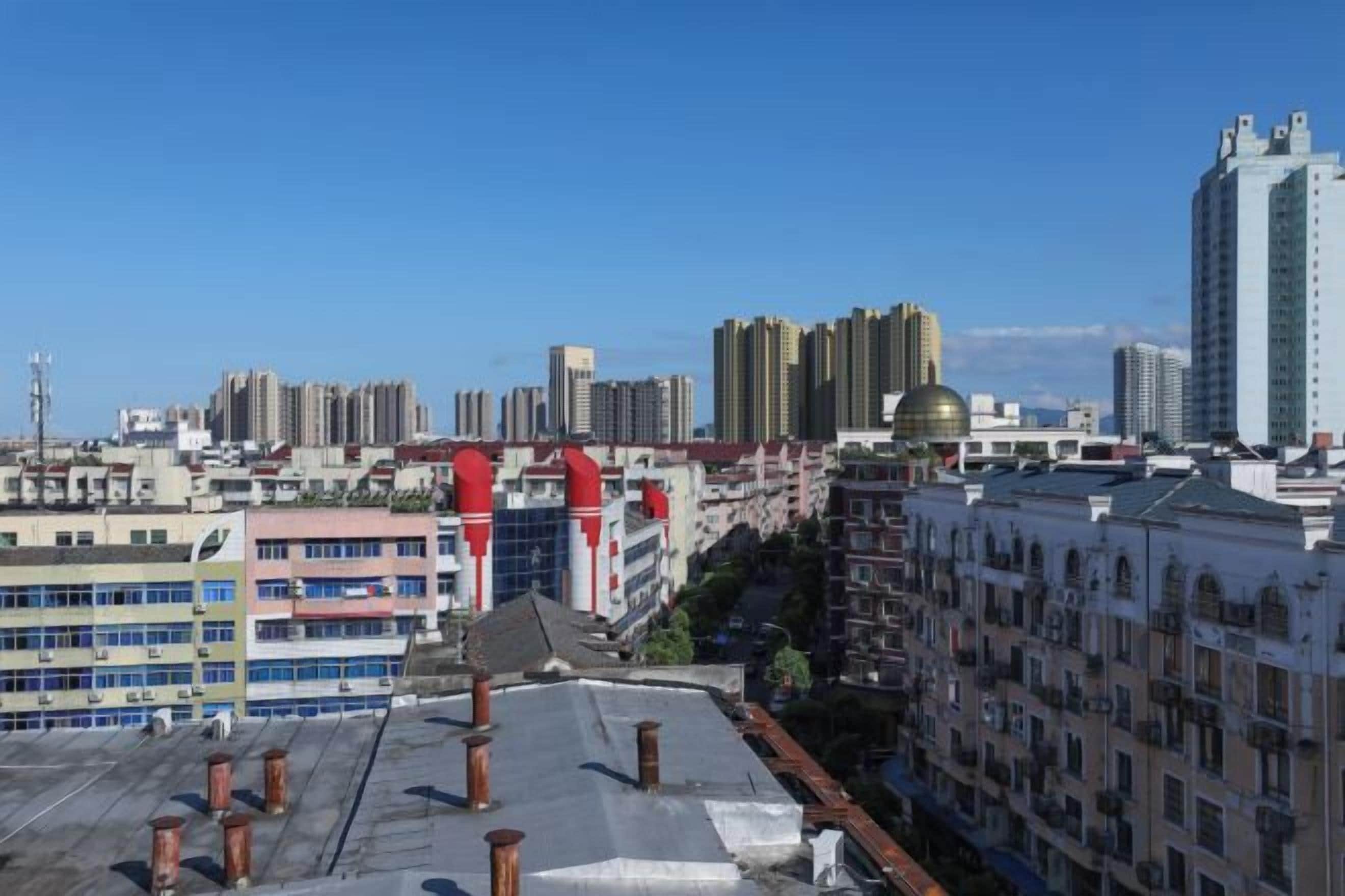 Un paysage urbain caractérisé par de hauts immeubles, un ciel dégagé et un mélange de bâtiments résidentiels et commerciaux.