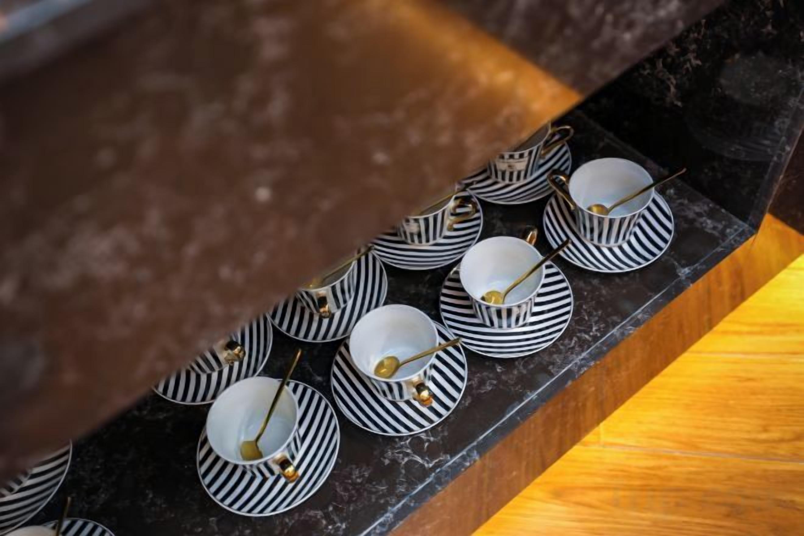 A series of black and white striped cups and saucers arranged on a dark surface.