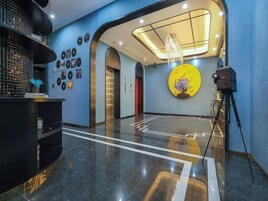 Un vestíbulo de hotel con una recepción, una gran obra de arte circular en la pared y una cámara sobre un trípode.