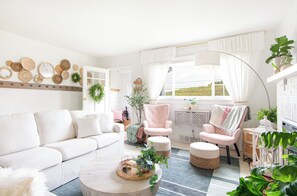 Una sala de estar moderna con un sofá blanco, una mesa de centro redonda y un sillón rosa.