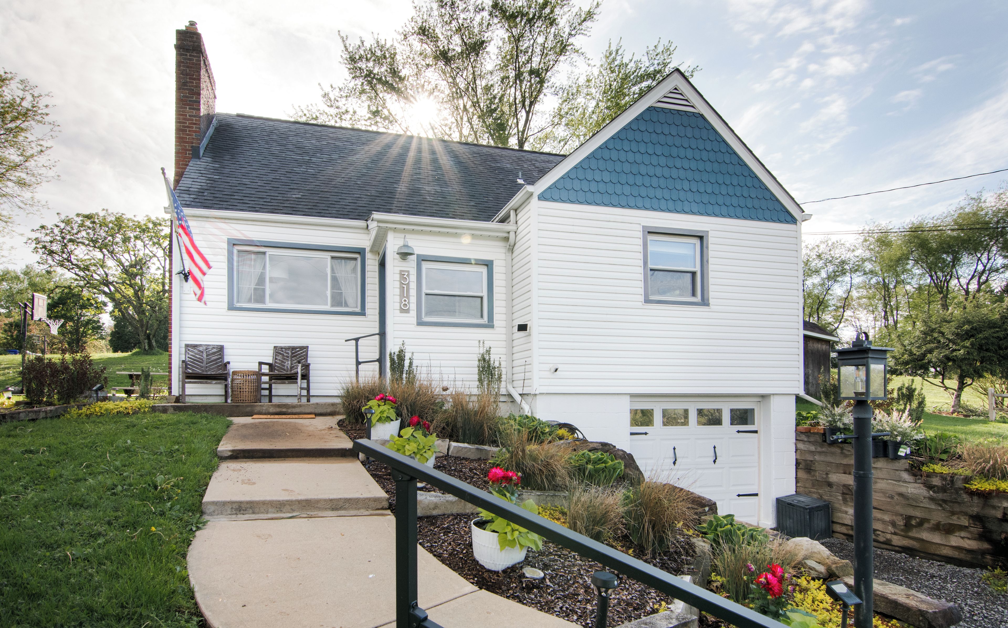 A two-story house with a front porch, a garage, and a well-maintained garden.