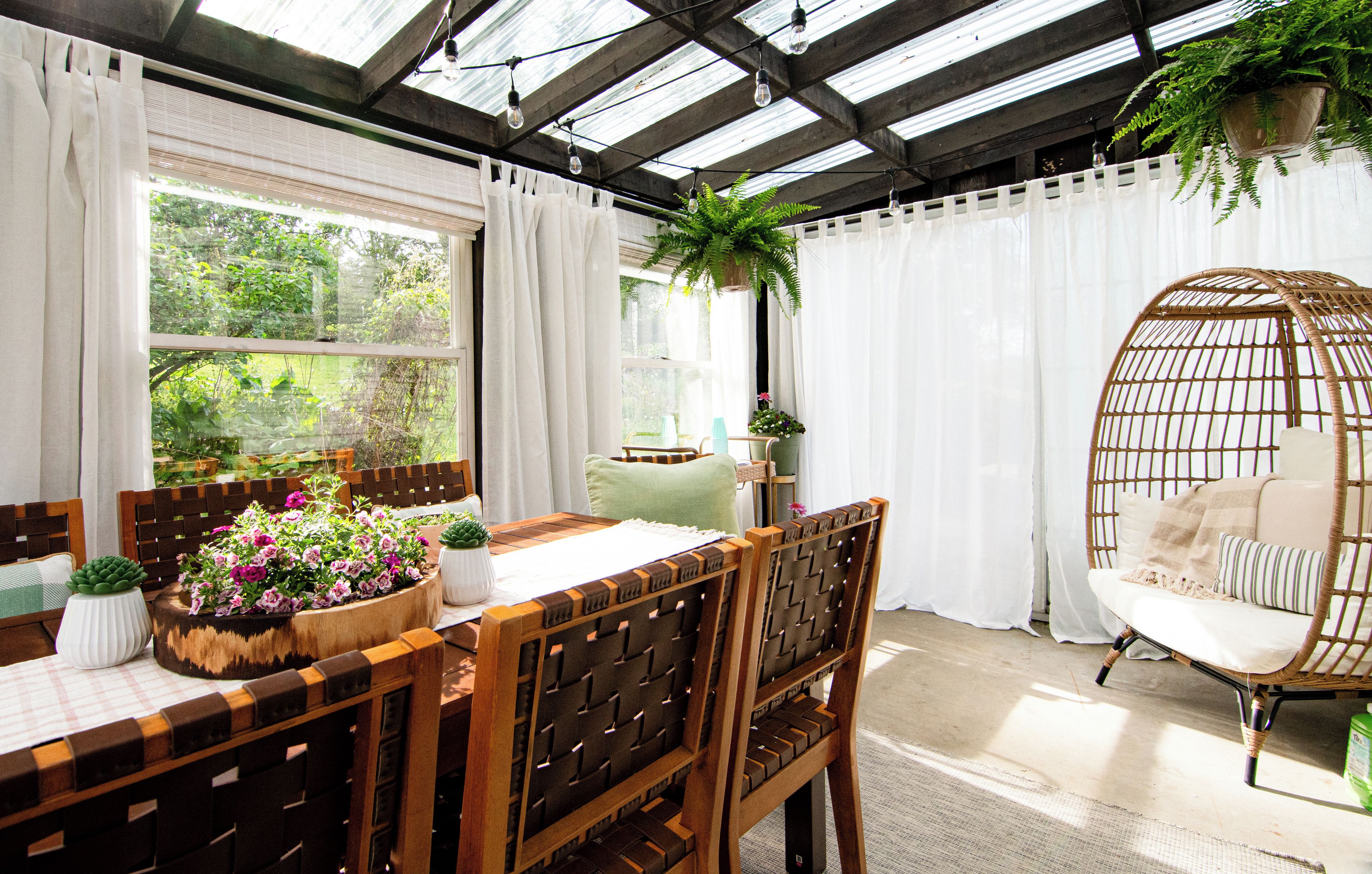 Una habitación con una mesa de madera, sillas, una silla colgante y plantas en macetas.