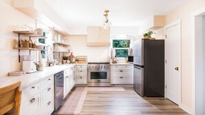Una cocina moderna con armarios blancos, electrodomésticos de acero inoxidable y piso de madera.