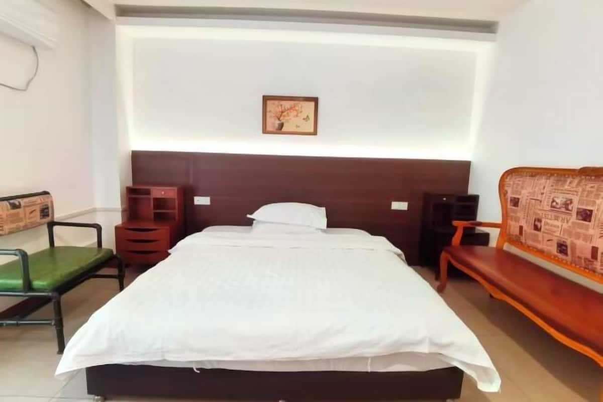 Une chambre d’hôtel comprenant un lit, une table de chevet, une chaise, un banc et un tableau accroché au mur.