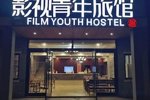 L'entrée d'un hôtel, avec un comptoir d'accueil, un espace salon et un escalier menant à l'étage supérieur.