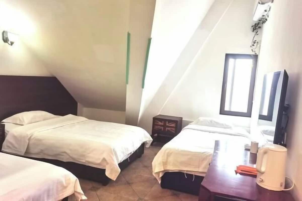 Une petite chambre accueillante avec deux lits, une table de chevet en bois, un miroir et une fenêtre.