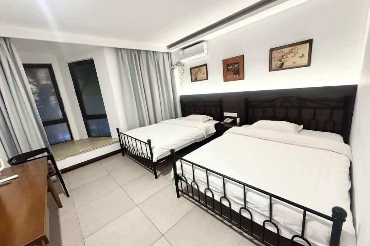Une chambre d’hôtel avec deux lits, un bureau et une chaise. Il y a trois tableaux encadrés au mur.