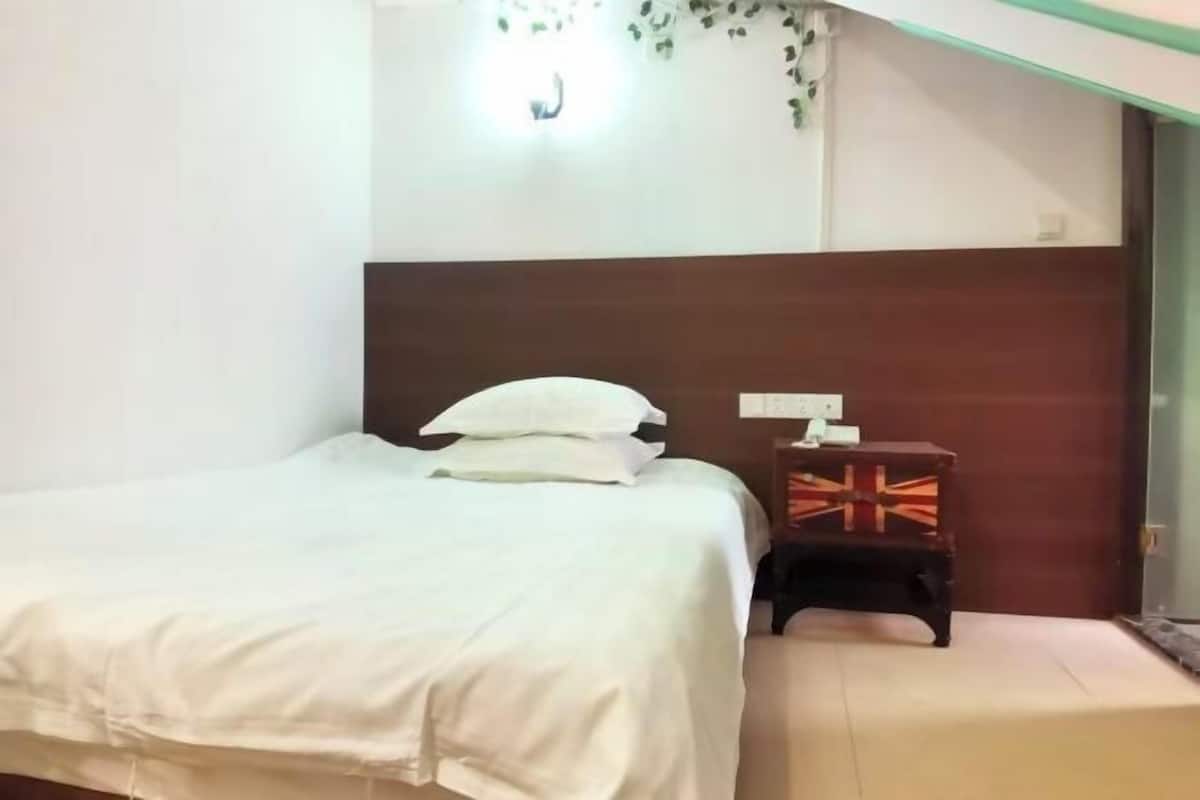 Une chambre à coucher avec un lit, des oreillers, une table de chevet avec une lampe et un luminaire fixé au mur.