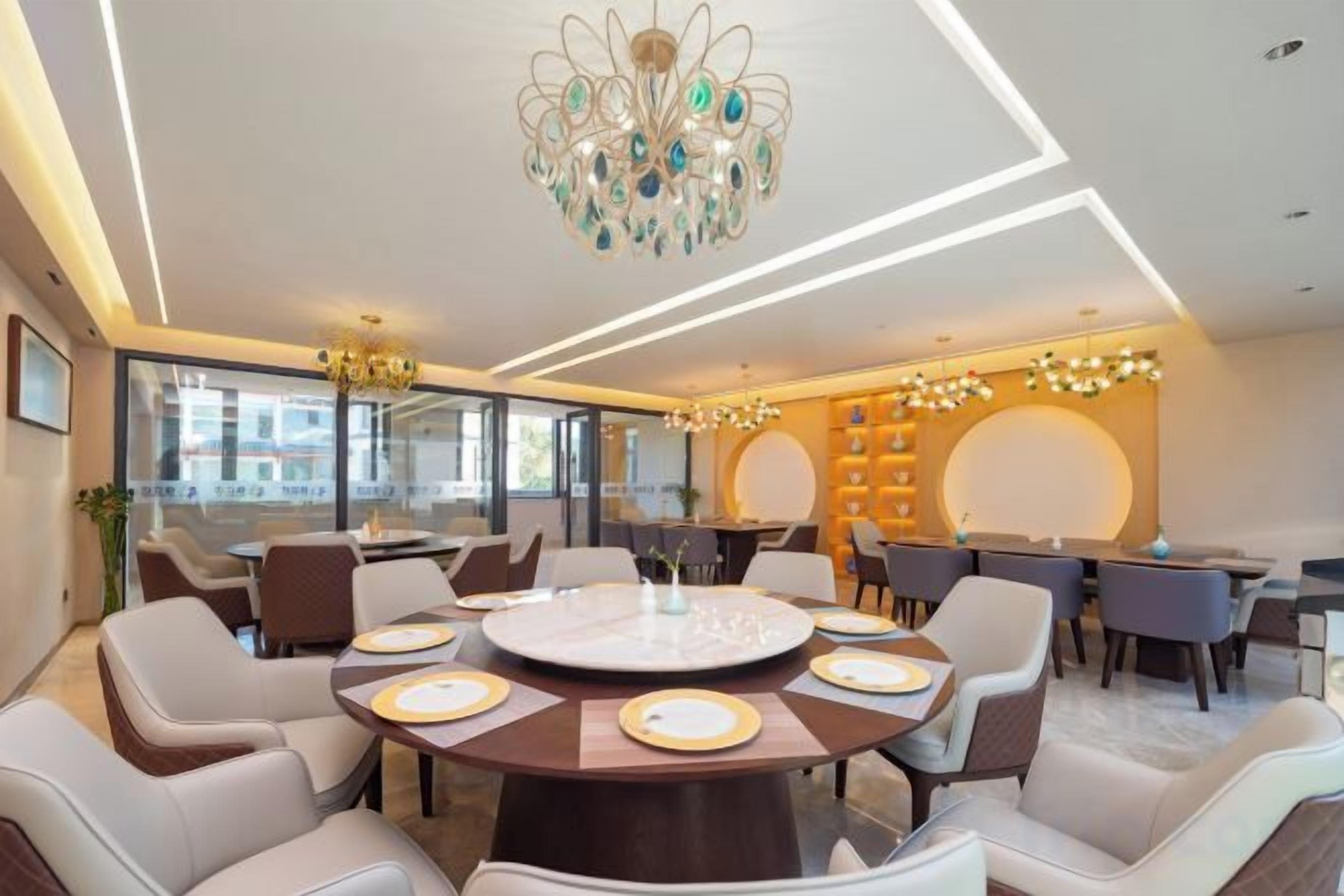 A modern dining area with a round table, multiple chairs, and a chandelier.