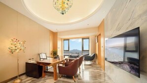 A modern hotel room with a dining area, large windows, and a view of the mountains.
