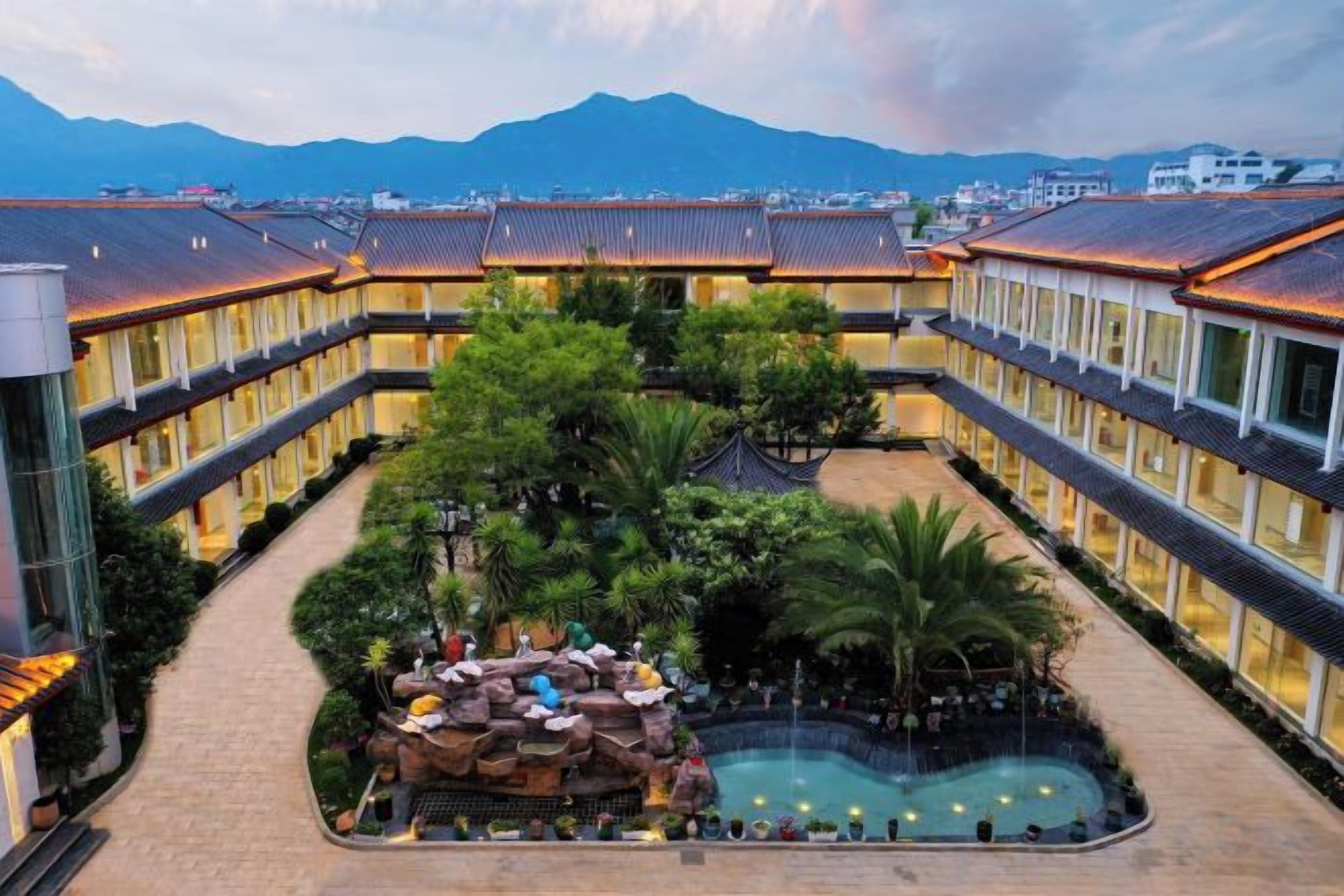A hotel courtyard with a pool, surrounded by buildings with traditional architecture.