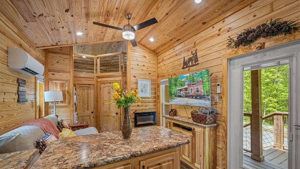 L’intérieur d’un chalet en bois comprend un coin cuisine, une table à manger et une cheminée.