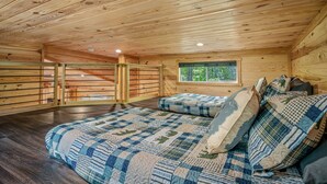 L’intérieur d’un chalet en bois, avec un lit, une fenêtre donnant sur un paysage agréable et un détecteur de fumée fixé au plafond.