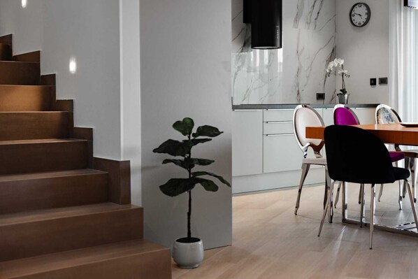 A modern kitchen with marble countertops, a dining area with a wooden table and chairs, and a staircase with a potted plant. - Villa DIVA II with private pool (Kras)