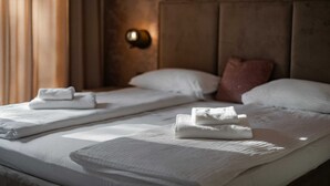Et hotelværelse med to senge, hver med pænt foldede hvide håndklæder.