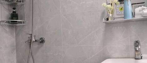 A bathroom with a shower, a sink, and storage shelves.
