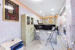 A hotel reception area with a reception desk, chairs, a cabinet, and a wall-mounted display. - Ping'an Hotel (Shanghai)