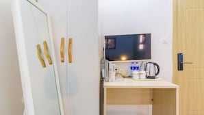 A room with a white wardrobe, a wooden desk with a television, a kettle, and some books. - Ping'an Hotel (Shanghai)