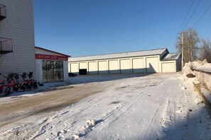 A snow-covered industrial area with a building that has a garage door and a sign. - Jinkelai Hotel (Huma)