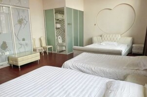 Una habitación de hotel con dos camas, un adorno en forma de corazón en la pared, un armario y un espejo.