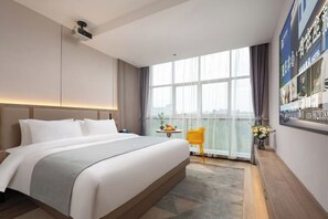 A modern hotel room with a large bed, a small table with a vase of flowers, and a view of the city through large windows. - Skyscraper Hotel (Wenling Jingyuan Branch) (Wenling)