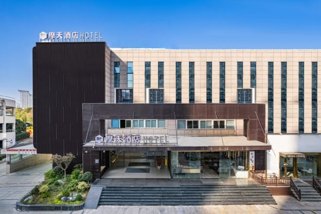 A hotel with a modern facade, featuring a prominent sign and a well-maintained entrance area with steps leading up to the main entrance.