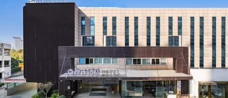 A hotel with a modern facade, a prominent entrance, and a landscaped area in front.
