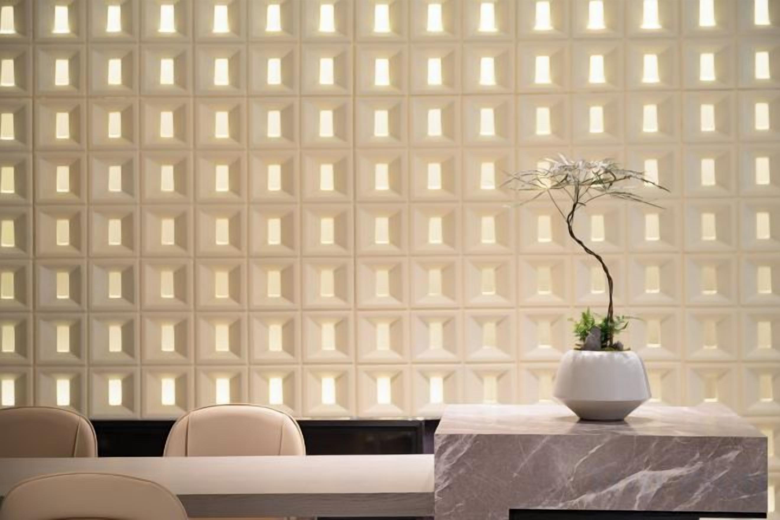 A reception area with a marble table, chairs, and a potted plant against a patterned wall.