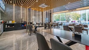 A modern restaurant interior with a wooden ceiling, marble walls, and large windows offering a view of the outside. - Skyscraper Hotel (Wenling Jingyuan Branch) (Wenling)