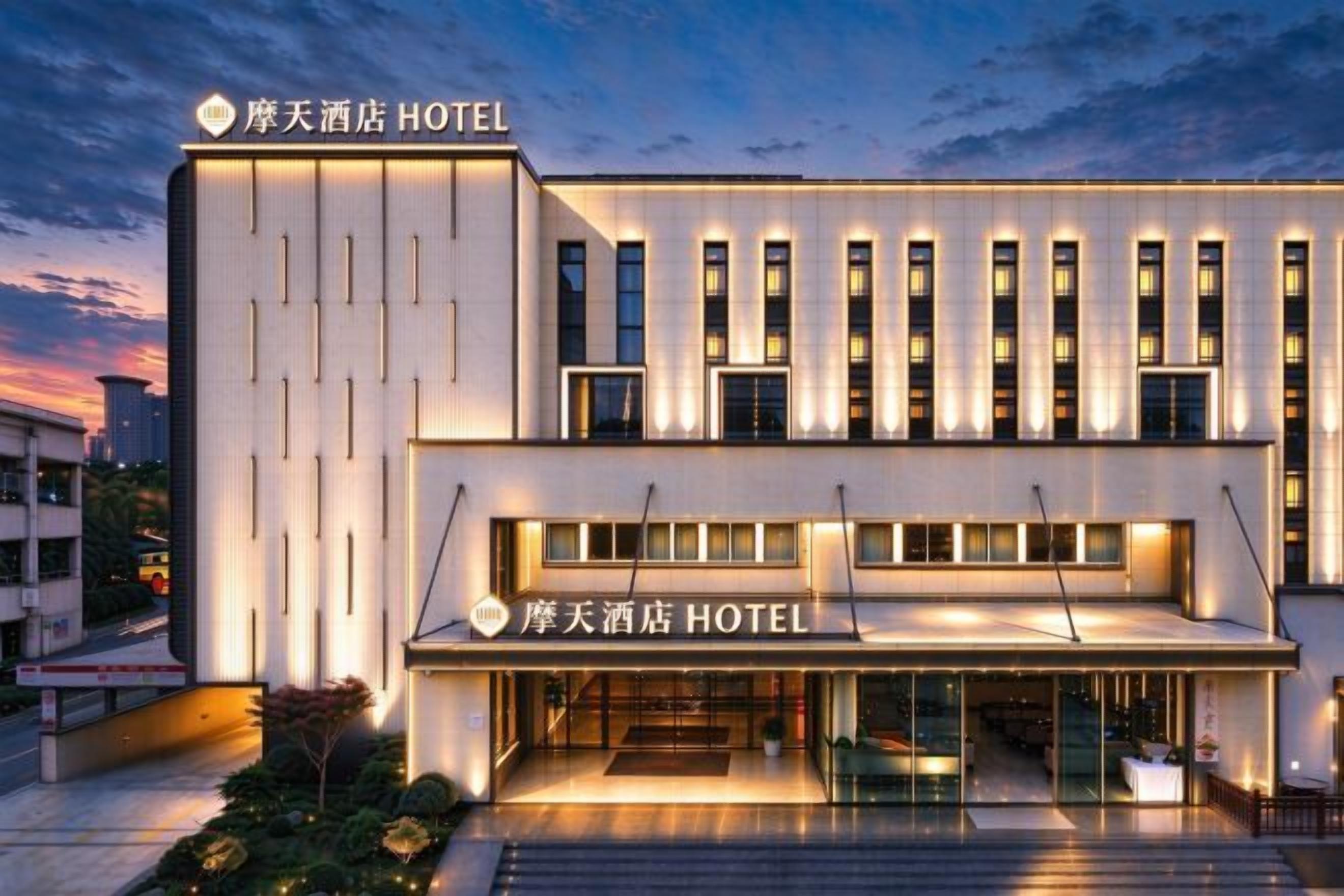 Un hotel moderno con una entrada destacada, varios pisos y señalización iluminada.