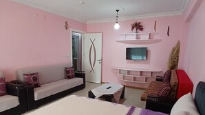 Ein Schlafzimmer mit einem Bett, einer Couch, einem an der Wand befestigten Fernseher und einem kleinen Tisch.