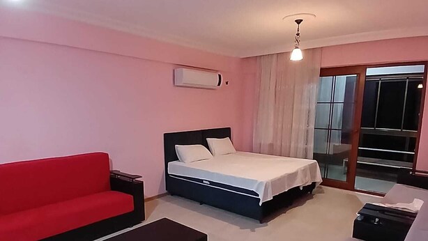 A hotel room with a bed, a red sofa, a black coffee table, and a white couch. - Mehmet Home (Denizli)