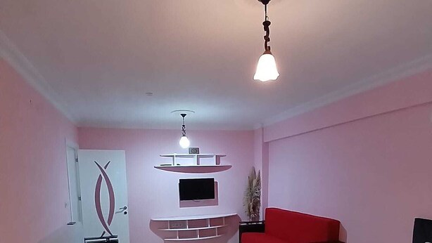 Ein Hotelzimmer mit Bett, Sofa, Wandfernseher und Deckenleuchte.
