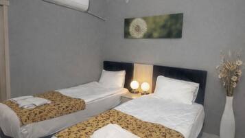 Une chambre d’hôtel avec deux lits, une grande fenêtre et un climatiseur fixé au mur.