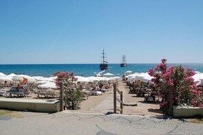 Ein Strandresort mit Liegestühlen, Sonnenschirmen und freiem Blick auf das Meer.
